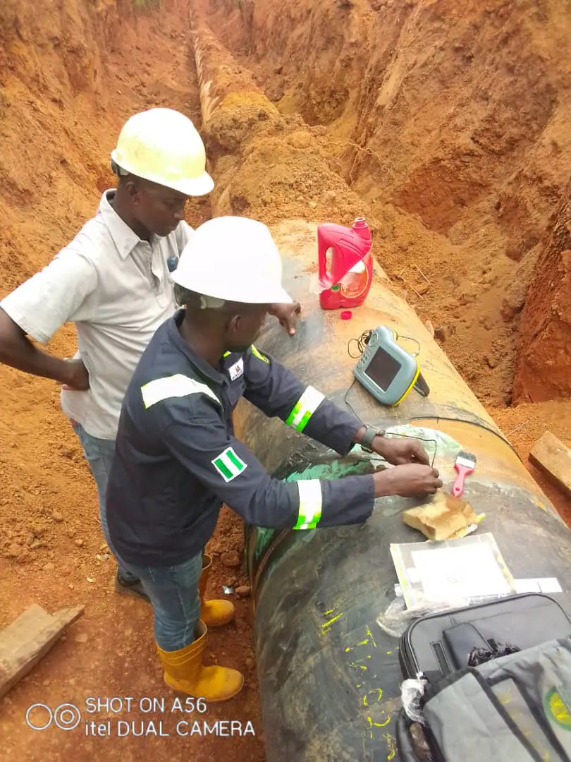 Technician conducting ultrasonic thickness testing on an exposed pipeline
