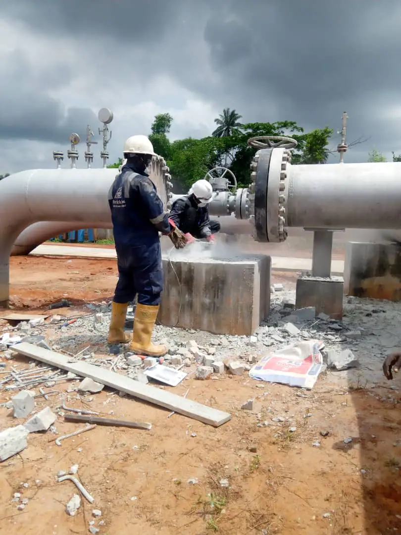 Technicians working around a valve and pipeline manifold at a field site